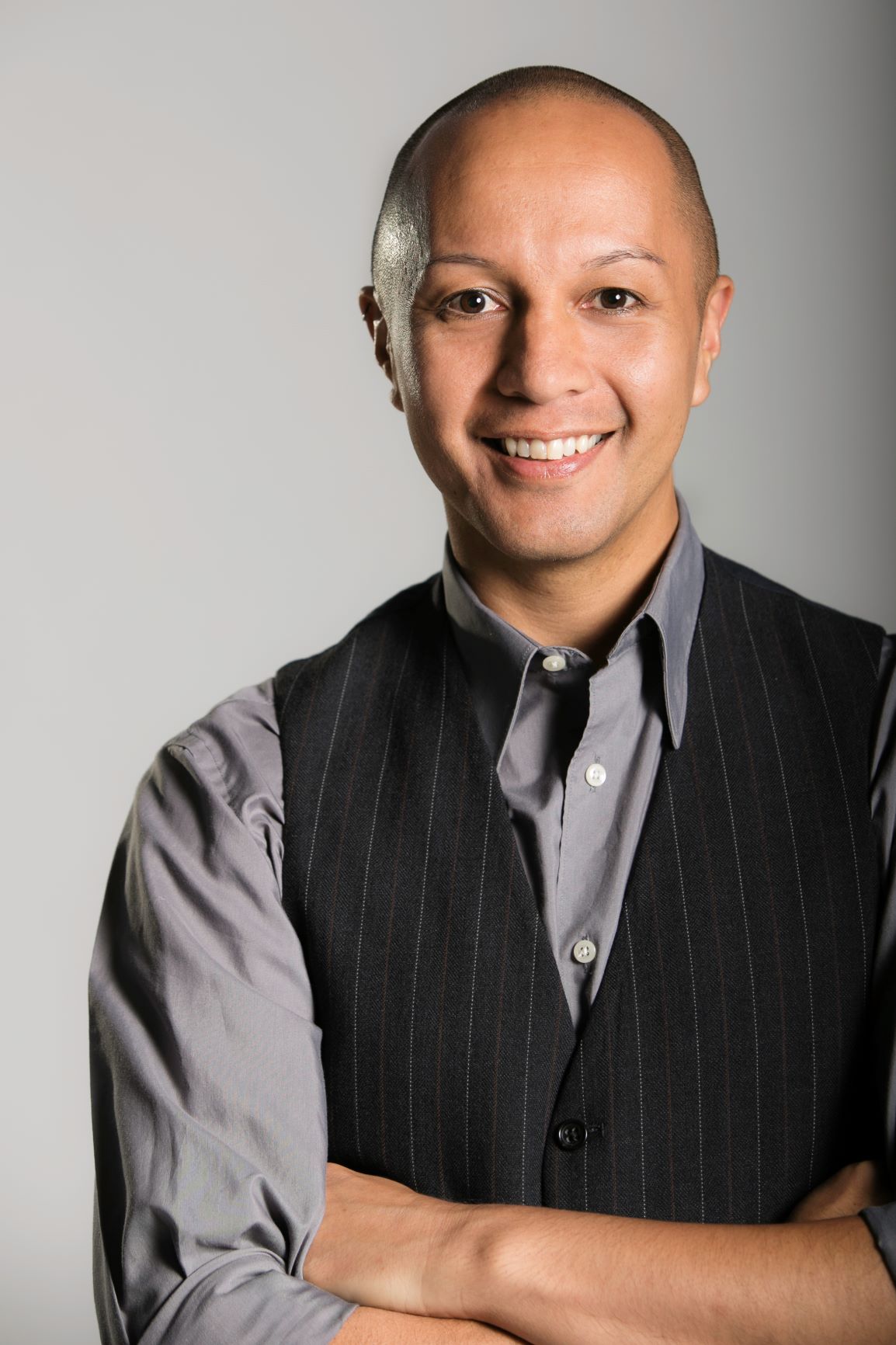 Man in black-and-gray garments smiles