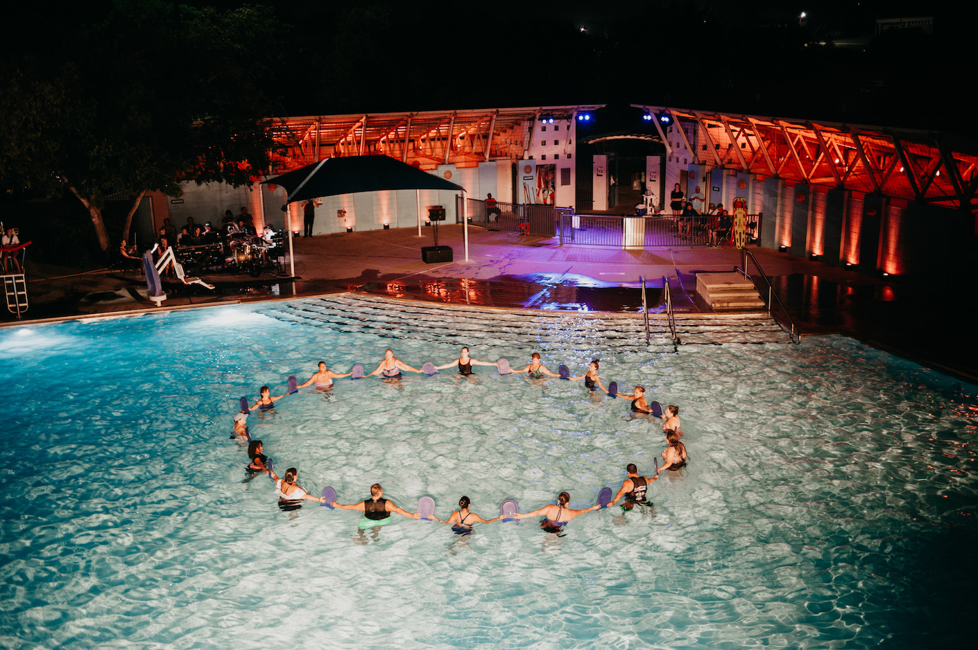 Large group of people form a circle in a swimming pool