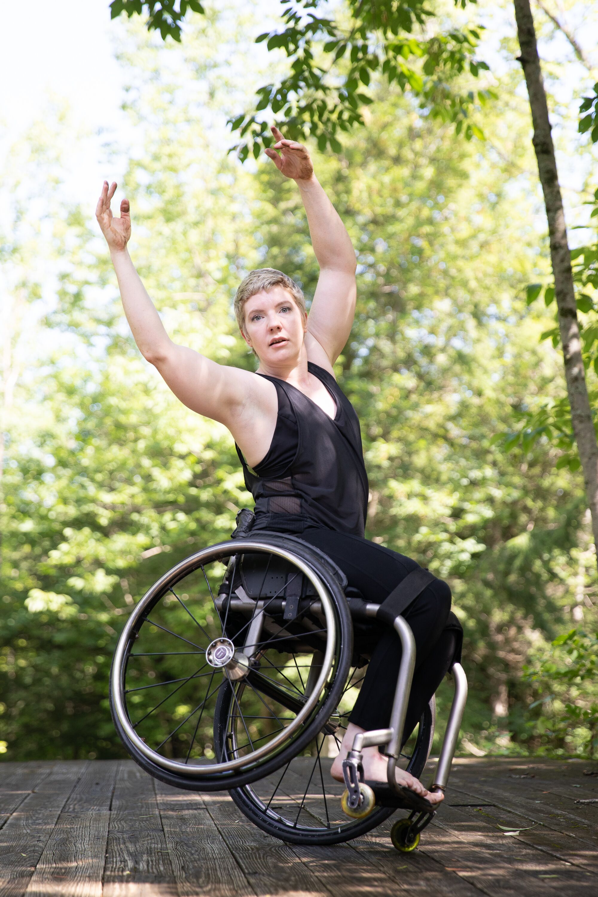 Lawson balances on one wheel, tilting away from the camera. She throws her arms overhead and looks at the viewer. Lush greenery is in the background. Lawson found that dance combined her lifelong loves of art and athleticism.