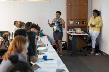 Group of individuals gaze at two women speaking