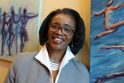 Woman smiles and stands in front of hanging portraits