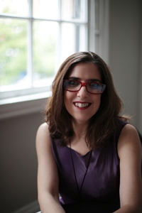 Woman in glasses seated next to a window