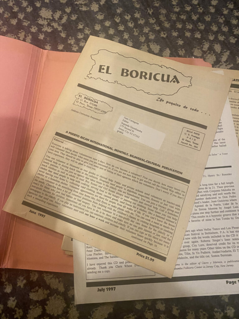 A pink folder open with papers inside reading "El Boricua" and covered in text