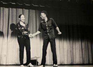 To dancers smiling and holding hands on stage